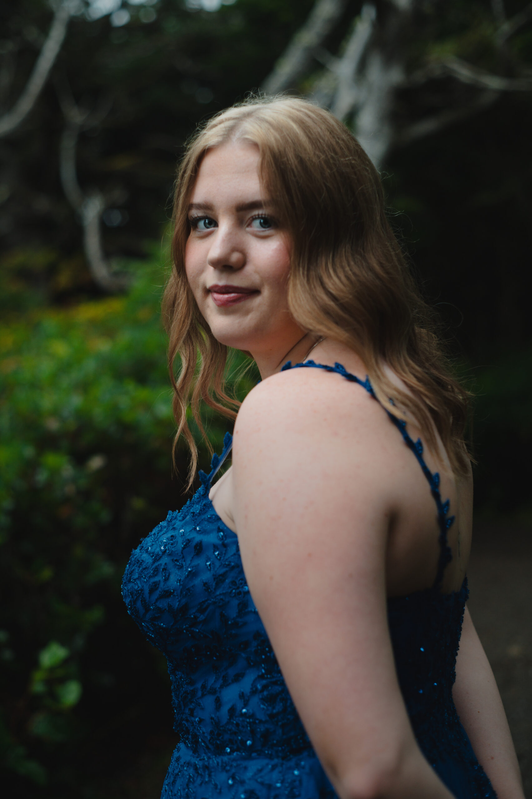 Amphitrite Point Lighthouse and rocky coastline with graduate in blue dress