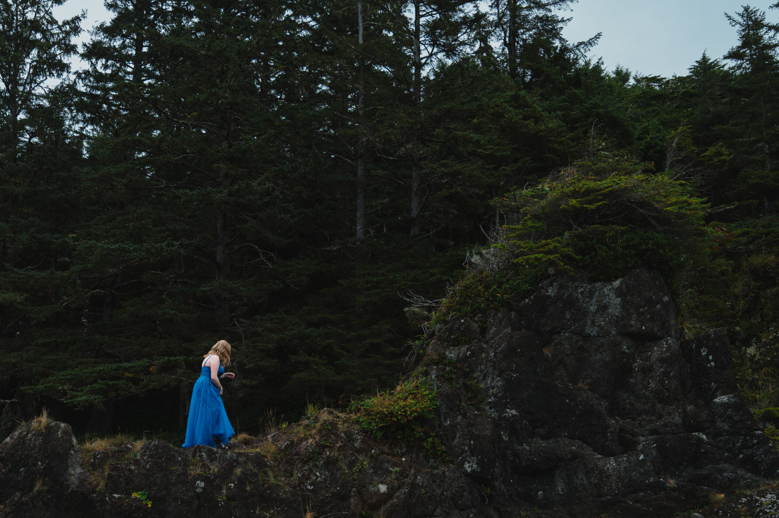 Graduate in blue dress standing on rocks at Amphitrite Point, Ucluelet